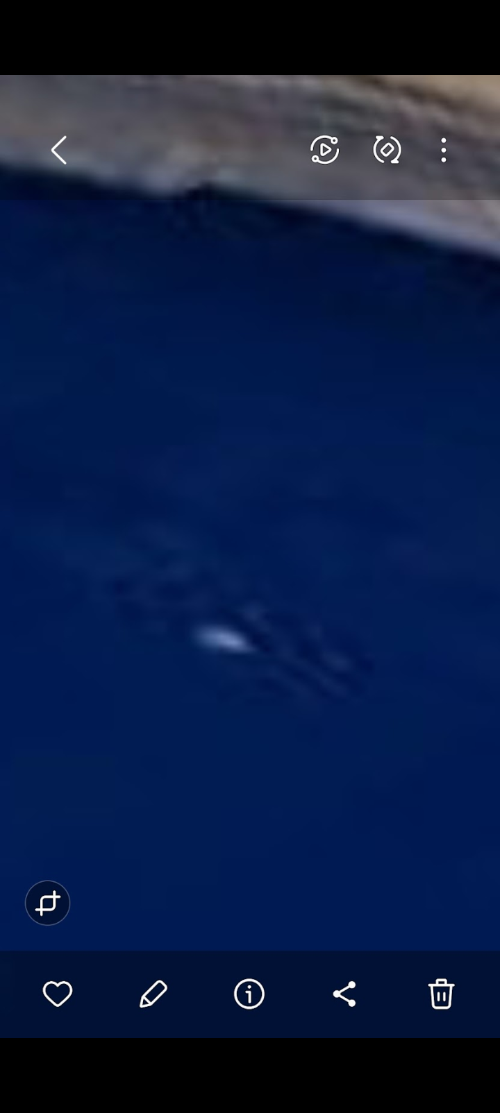 Tight zoom 2024 capture of a distinct arrow shaped luminous Unidentified Submerged Object visible beneath the dark blue surface of the Columbia River with a bright leading tip and a tapered trailing wake signature consistent with a submerged craft in motion not consistent with fish wildlife surface glint or recreational vessel signature at this coordinate within the Pacific Pulse Corridor envelope on the Washington side of the river along Highway 14