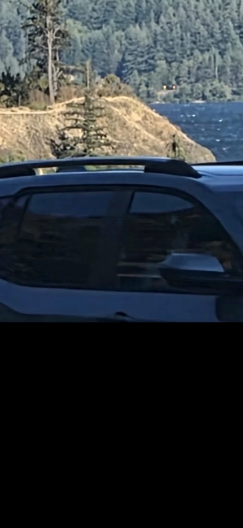 Wide shot of Mitchell Point across the Columbia River with a vehicle in the near-ground blocking the Perceiver's line of sight to the mountain face