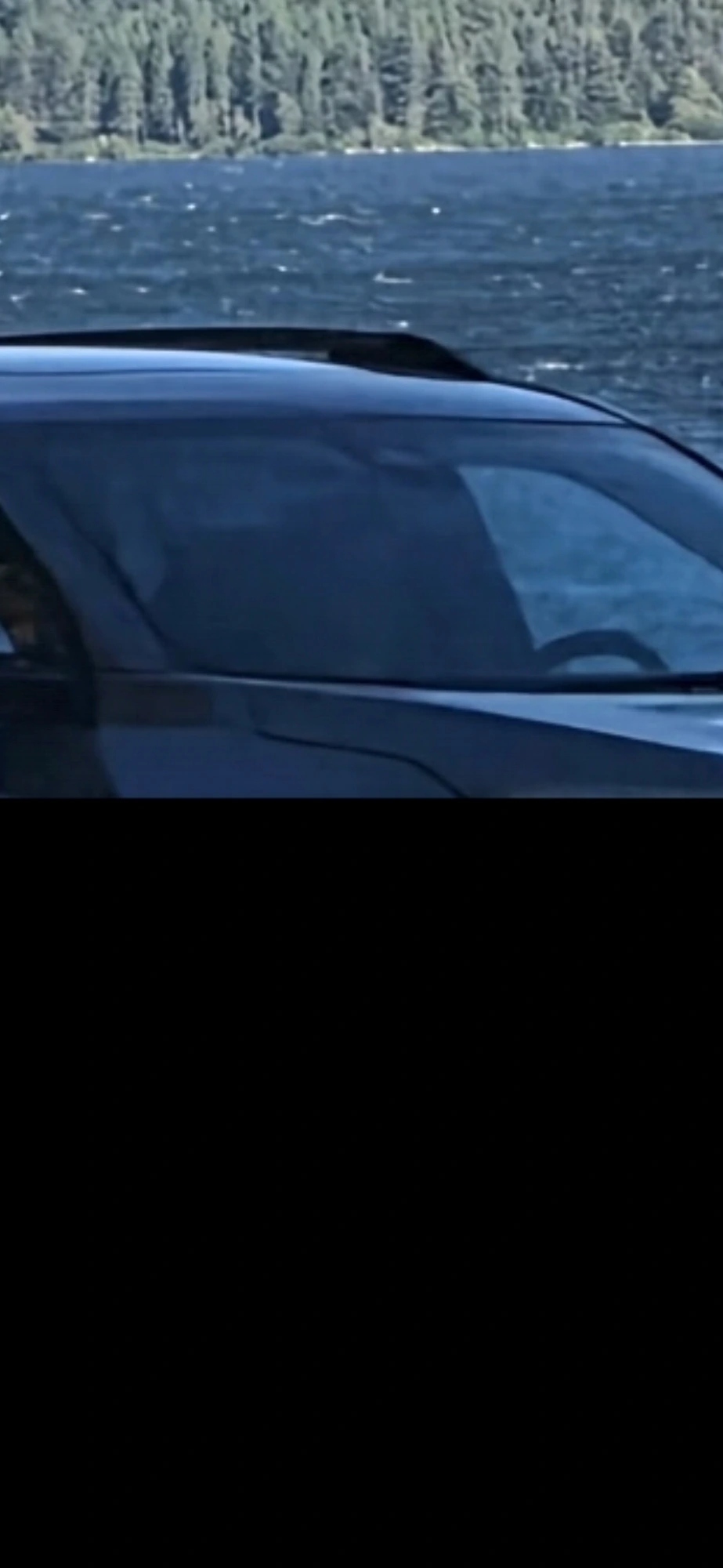 Zoom onto the passing vehicle showing the outline of two occupants behind the windshield