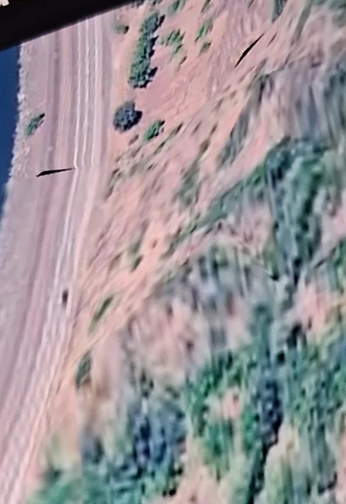 Google Earth ground-level view of a Columbia River shoreline showing dark linear tracks in the sand parallel to the water