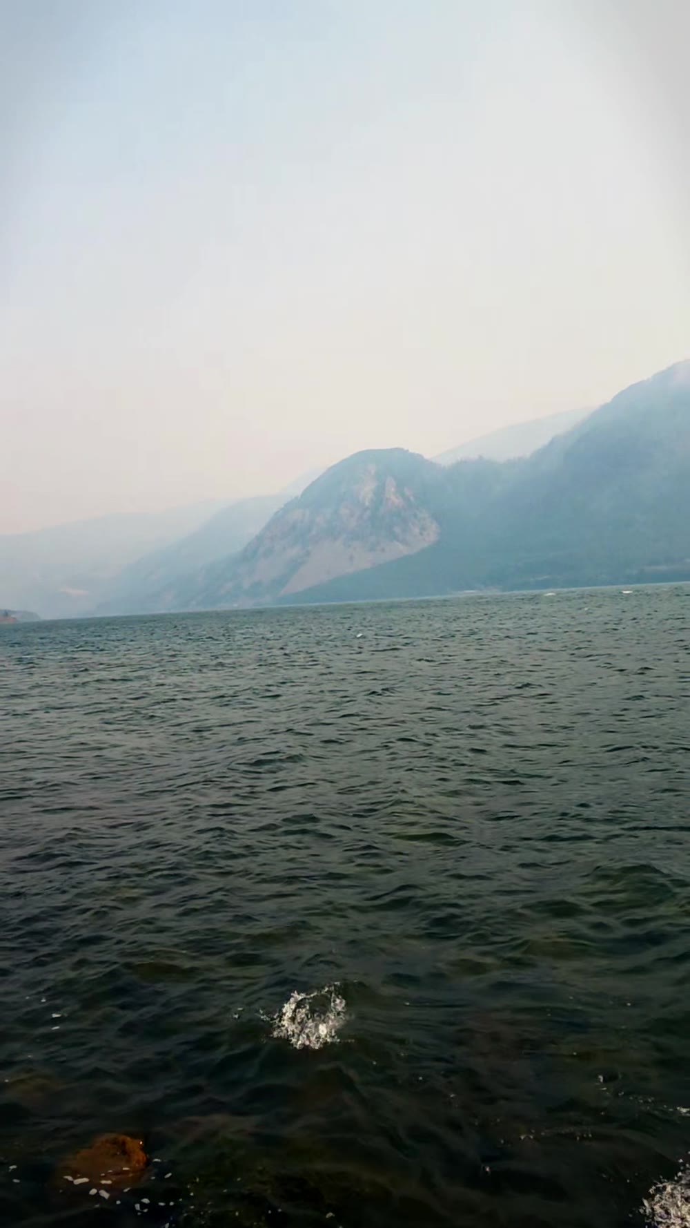 Wide view of the Columbia River with hazy mountains rising on the far shoreline and rippled mid-channel water