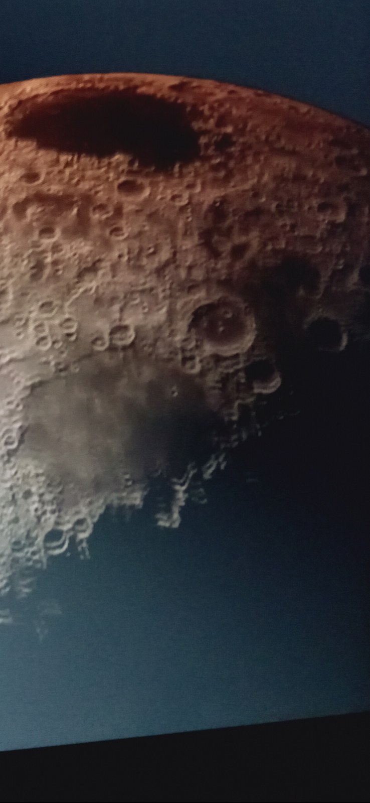 Direct field capture of the Moon by The Perceiver showing a dark elongated rectangular anomaly on the upper limb that does not match any known circular crater geometry — captured with a Samsung Galaxy A03s phone camera