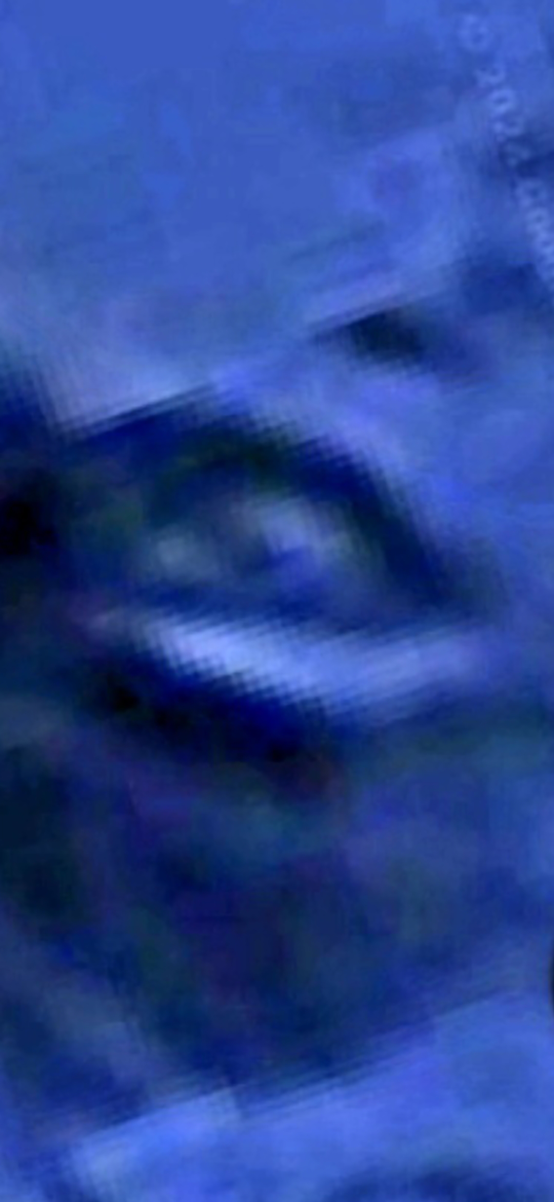 First zoom pass on the Mazatlán Pacific seafloor face showing the eye region resolving into a bright structured cuboidal or rounded geometry against the surrounding camouflaged blue seabed with hard edges and an internal bright core that the Perceiver reads as a possible flying craft sitting inside the recessed eye of the larger aquiferian face geometry
