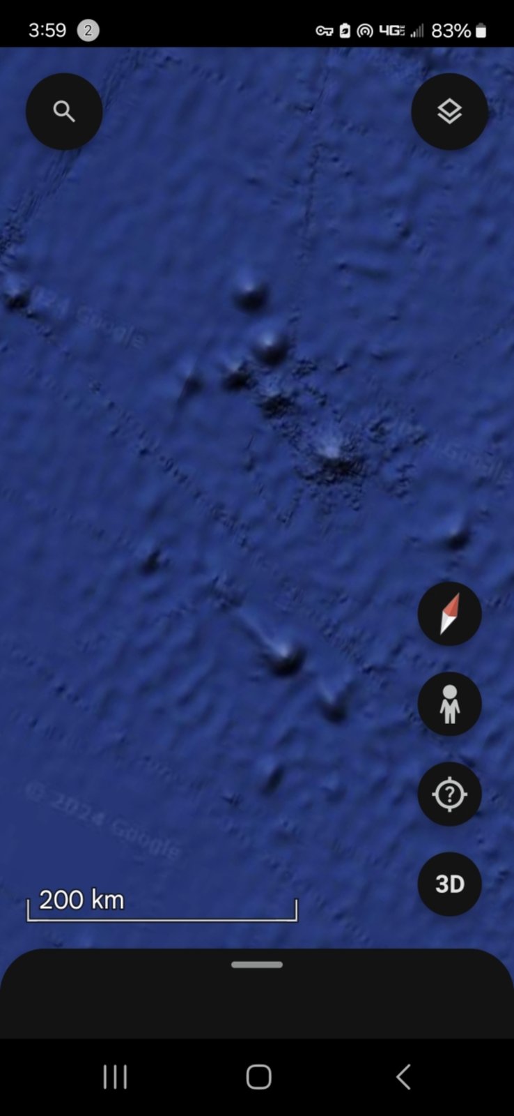 Wide field Pacific Ocean view at 200 kilometer scale showing a dispersed cluster of dark dome or seamount points across the open seafloor multiple discrete locations forming an extended network rather than a single isolated feature