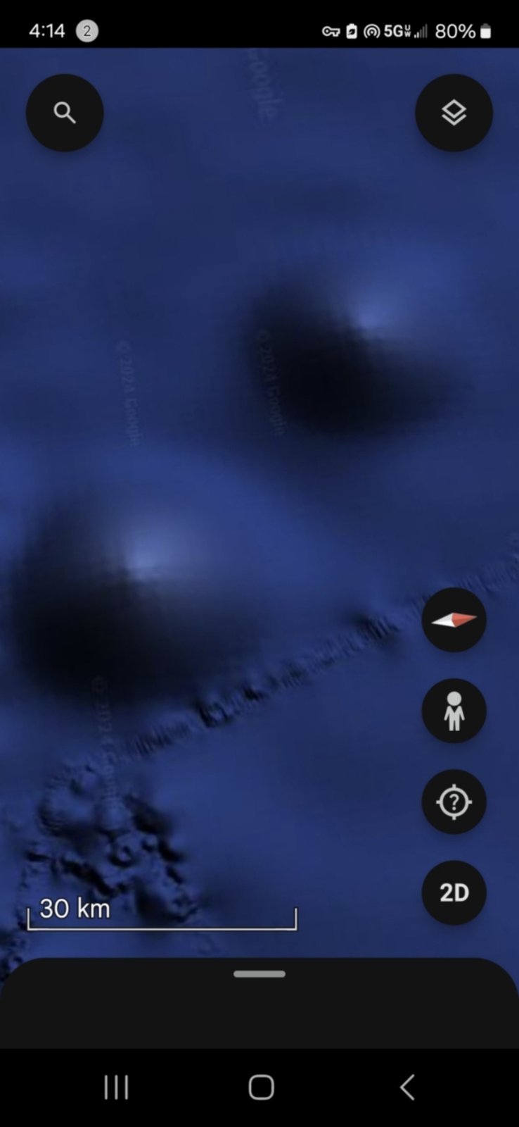 Two large concave dark zones with bright luminous central cores set into the Pacific seafloor at 30 kilometer scale separated by what appears to be a connecting ridge or boundary structure between them suggesting paired access points or paired vents