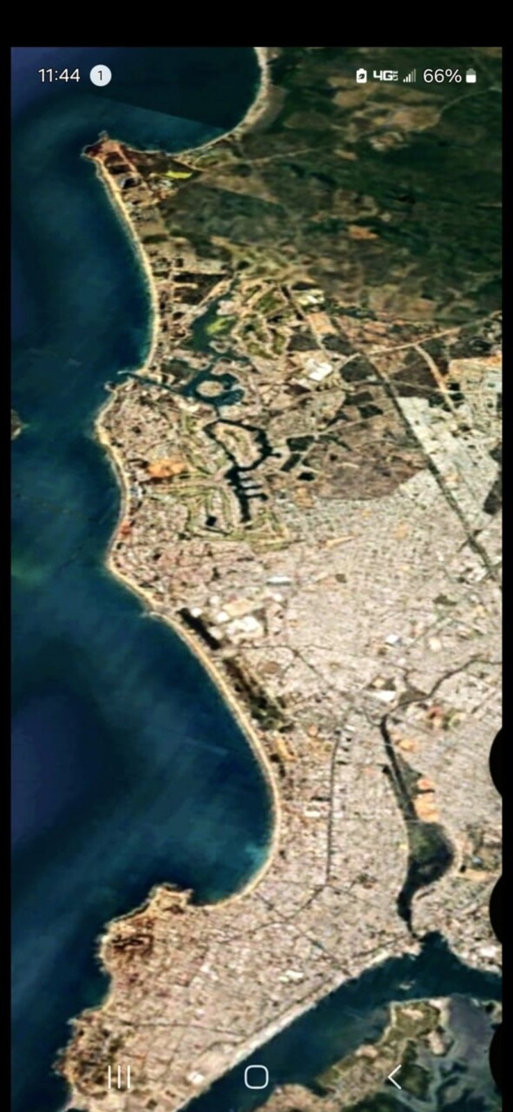 Wide aerial satellite view of the southern coastline of Mazatlán Mexico showing bay peninsulas and headland contours arranging into a discernible facial profile looking westward into the Pacific Ocean