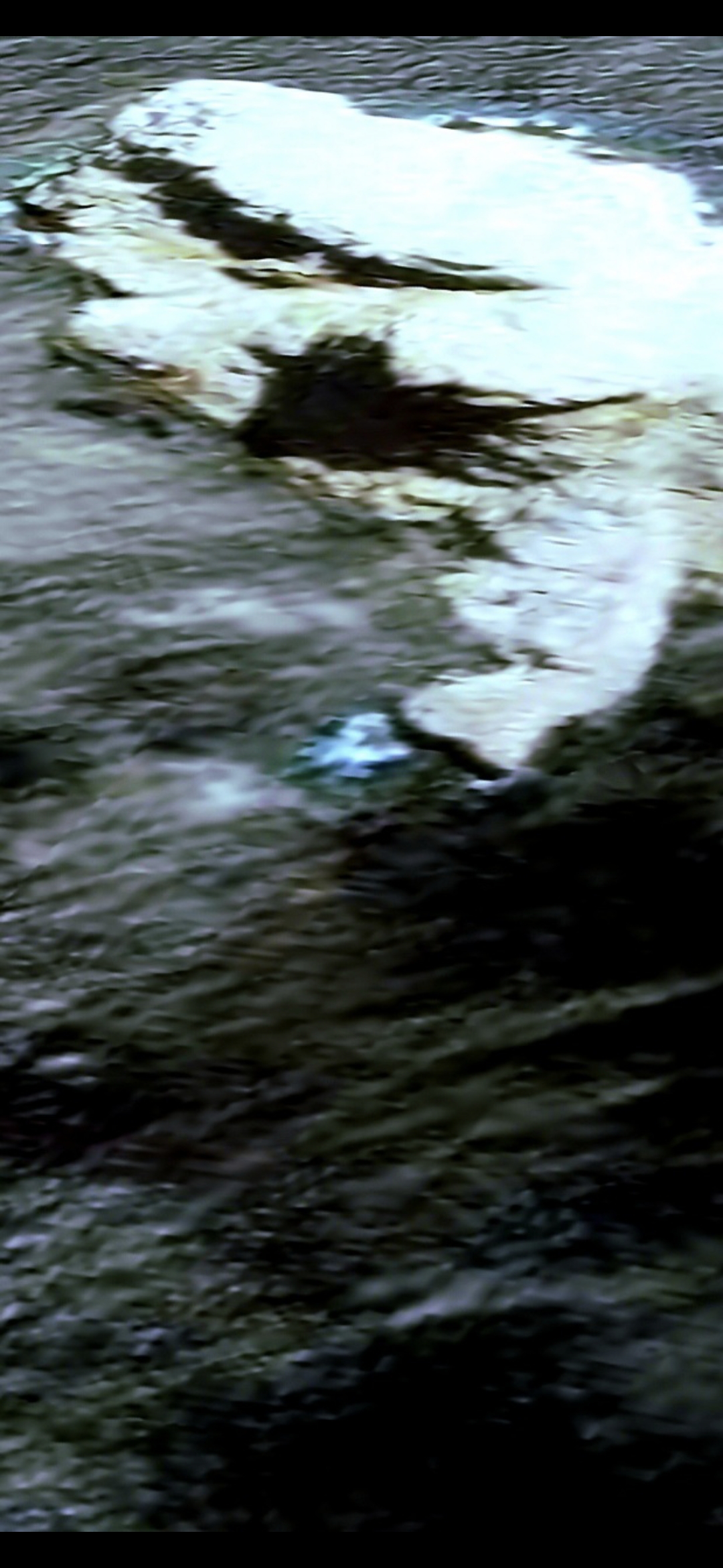 Aerial overview of a rocky landmass meeting dark water with a distinctly pointed eroded coastline feature resembling a water-exit point or sharp peninsula tip in the Mazatlán Pacific corridor flagged as a potential drainage or coastal access feature