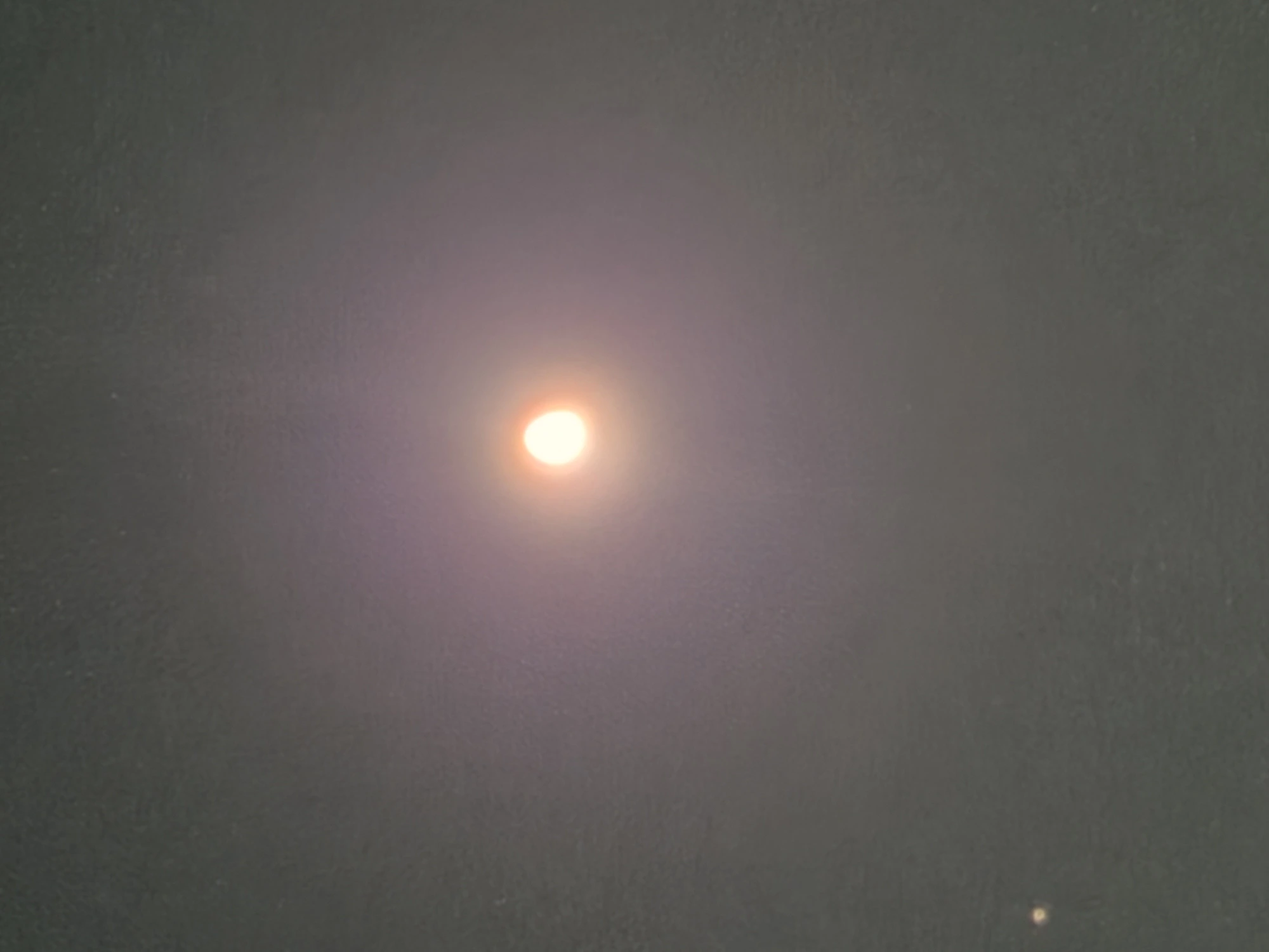 Wide-angle photograph of the same moon over the Columbia River Gorge showing atmospheric haze and the moon at distance