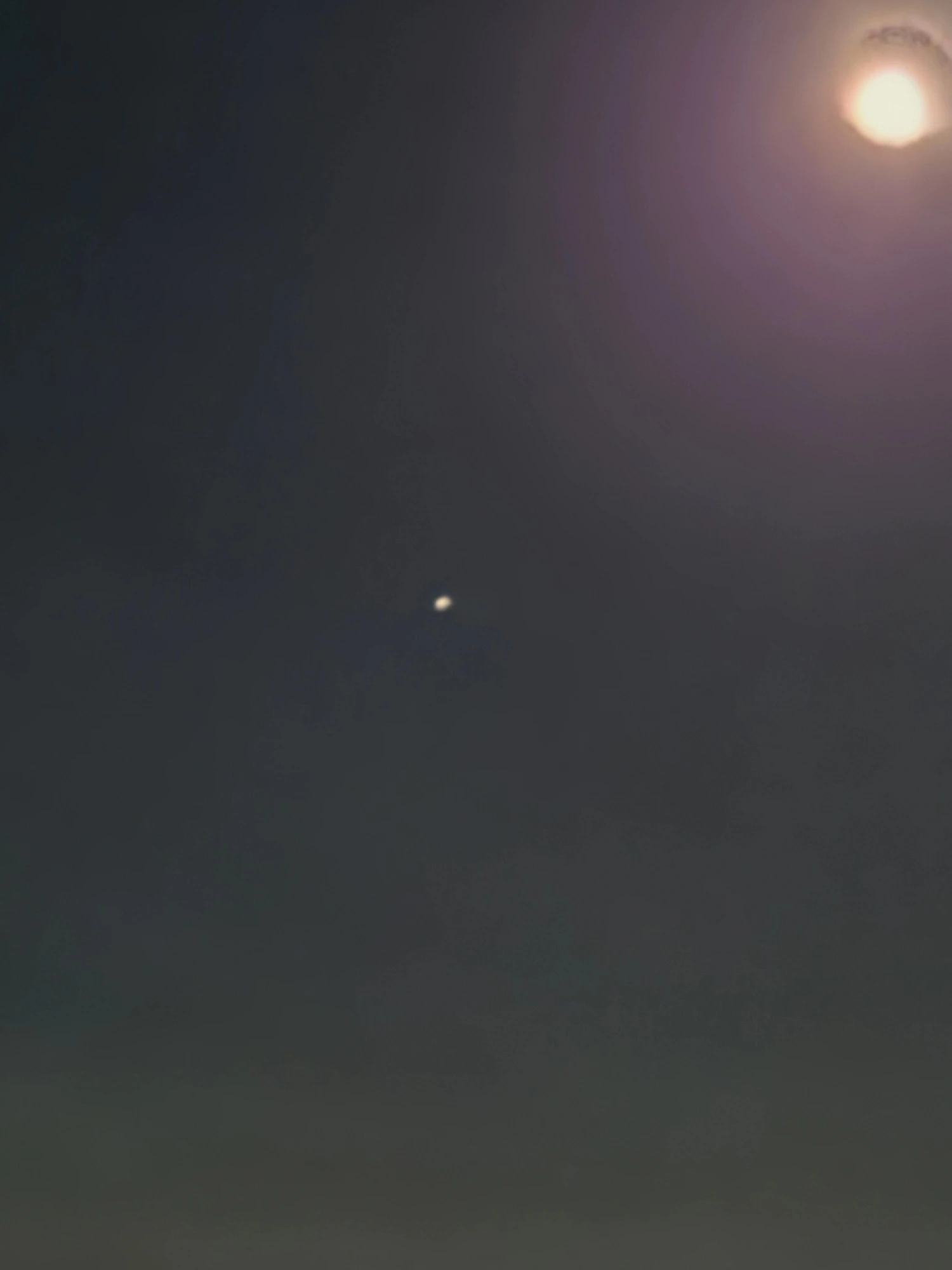 Portrait photograph of the same moon with a bright pinpoint sitting center-frame at a marked distance from the disc — the primary star-mimic object photographed at a second angle