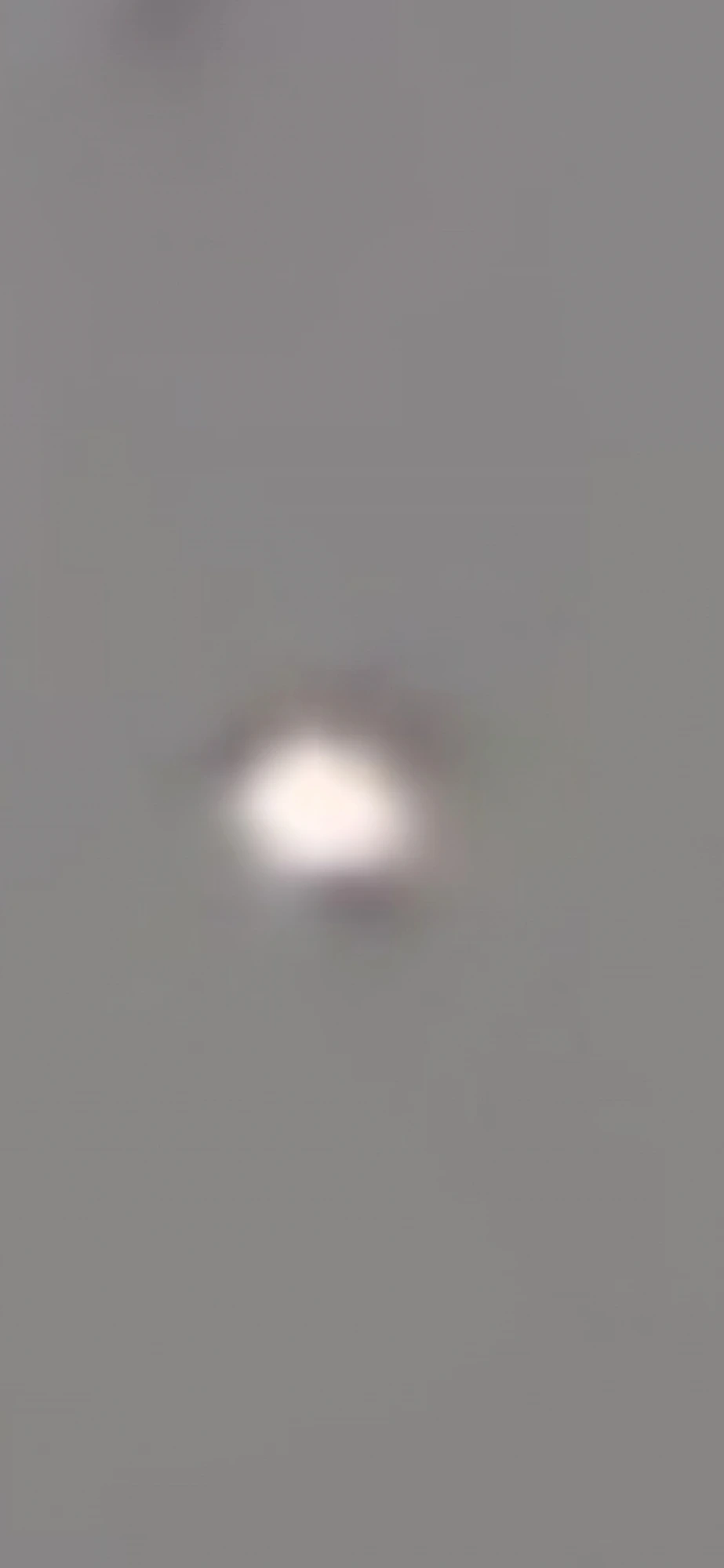 Second zoom frame — the orb resolves as a soft-edged bright form rather than a pinpoint, with faint dark shading beginning to appear along the upper hemisphere