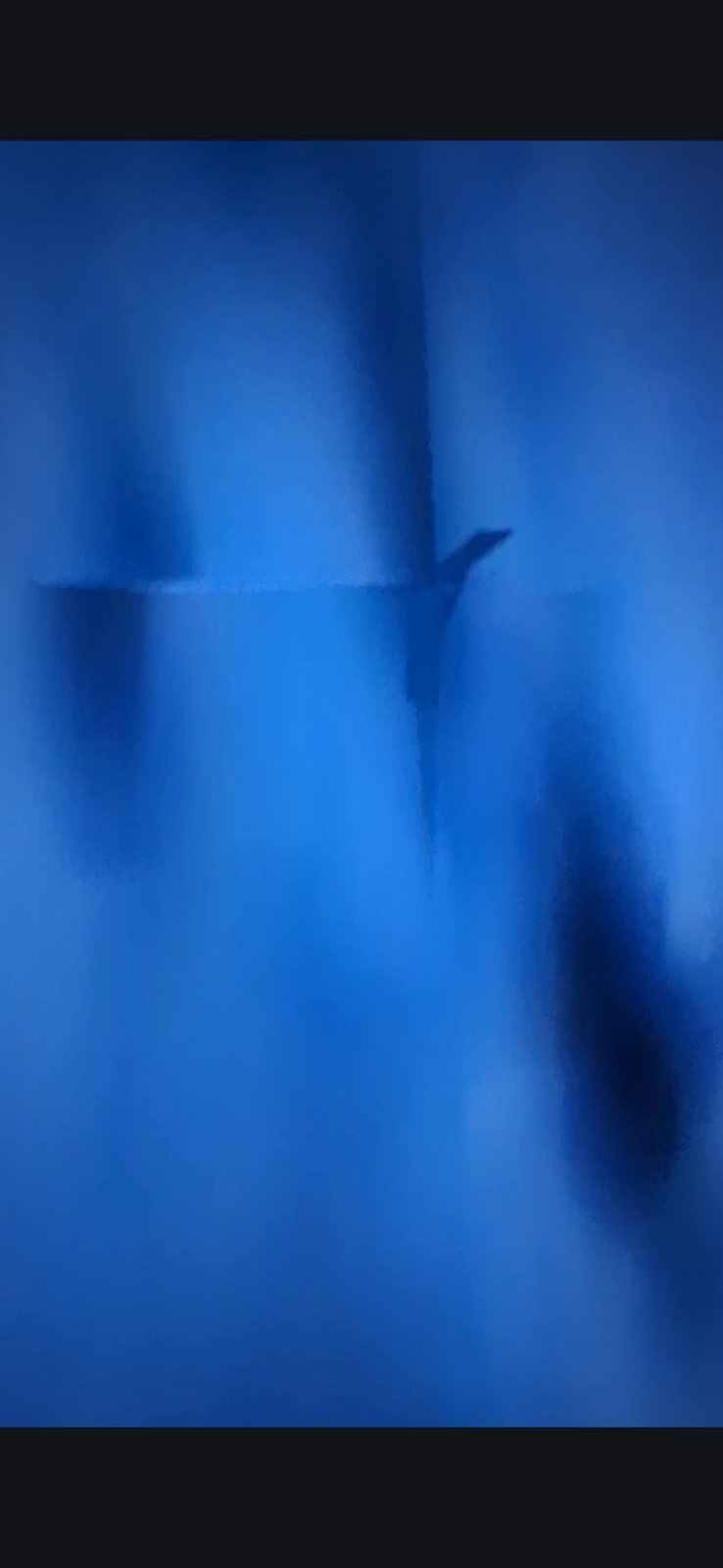 Pacific underwater installation second frame showing a long vertical shaft or column descending through the blue camouflaged water with secondary darker forms visible to the right