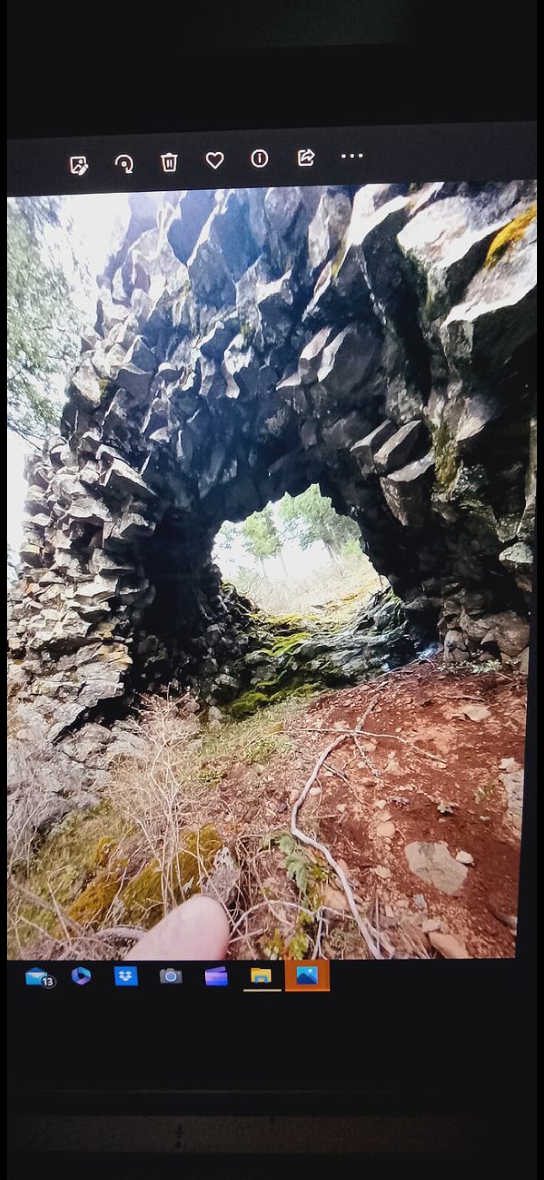 Wide view of the rock bridge interdimensional portal entrance showing the natural stone archway and surrounding volcanic terrain