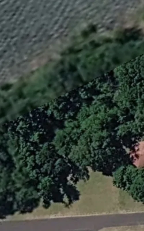 Overhead satellite view of Home Valley Park showing the central structure with a red roof surrounded by dense green treeline and a road running along the bottom of the frame