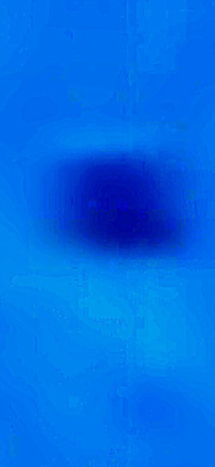 Macro close-up of a single round dropped particle suspended against the blue sky showing a soft trailing shadow underneath suggesting downward motion or an optical drag effect from the descent